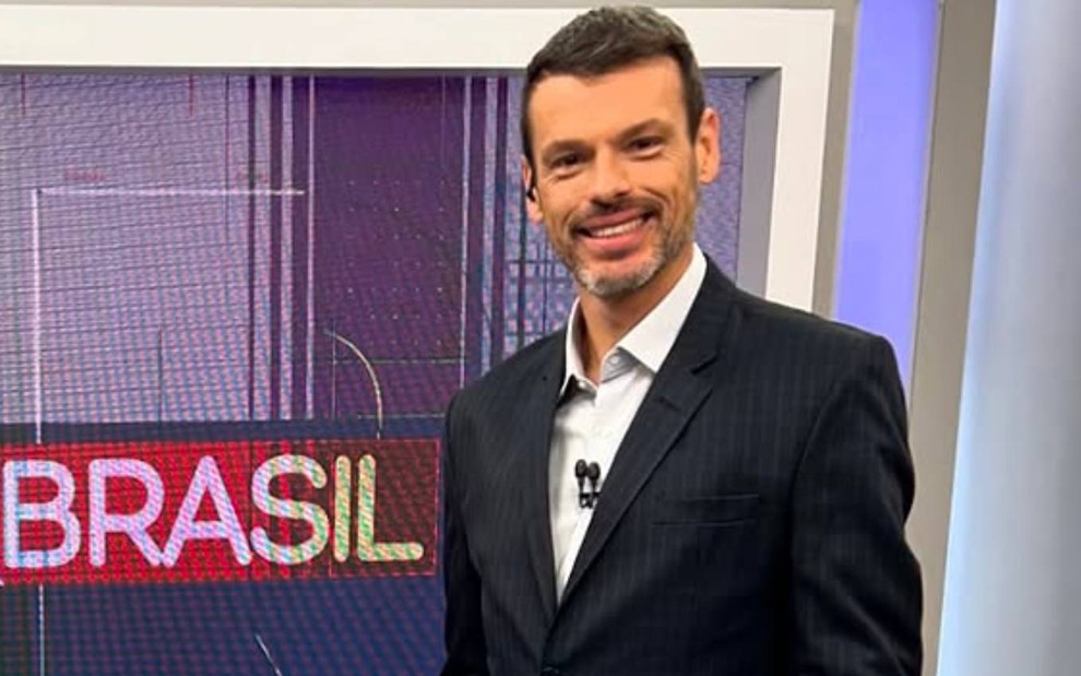 O repórter e apresentador sorrindo Lucas Martins no estúdio do Bora Brasil, na Band