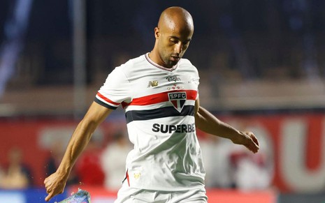 Lucas Moura faz movimento de chute na bola em jogo do São Paulo; ele usa o uniforme tradicional do clube
