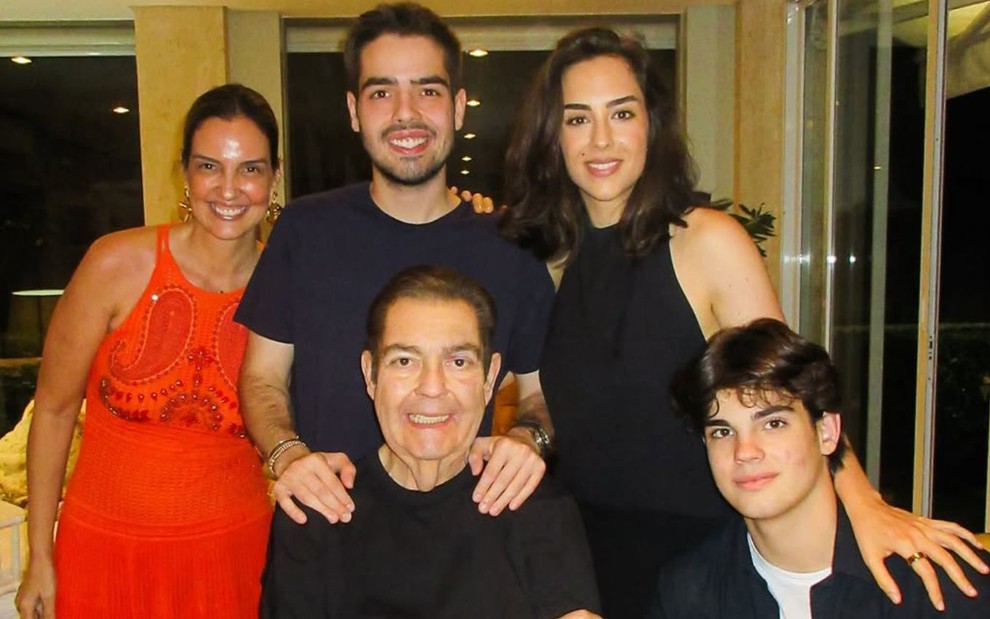 Luciana Cardoso, João Guilherme Silva e Lara Silva estão em pé; sentados no sofá estão Fausto Silva e Rodrigo Silva
