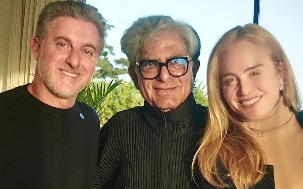 Luciano Huck, Deepak Chopra e Angélica sorridentes lado a lado, usando roupas pretas
