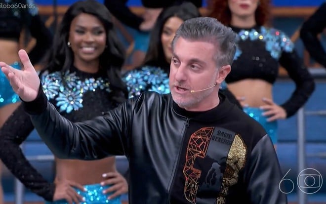 O apresentador Luciano Huck levanta o braço direito no palco do Domingão