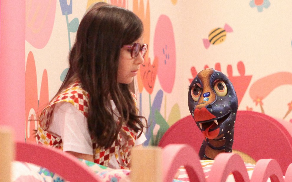 Isadora (Manu Bistene) conversa com uma cobra de pelúcia em cena da novela A Caverna Encantada
