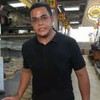 Marcelo Pereira usa uma camiseta preta e está num galpão cheio de panelas de barro