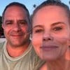 Patrick e Maria Cândida sentados na praia, sorridentes, de frente para a luz do pôr-do-sol
