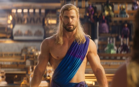 Chris Hemsworth está sem camisa, com uma túnica cobrindo parte de seu ombro