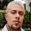 MC Daniel posando em frente a uma piscina, com uma jaqueta off-white, cabelo loiro e cavanhaque castanho