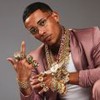 MC Poze do Rodo posando com um terno rosa brilhante, exibindo colares e anéis de ouro