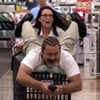 Megan Mullally empurrando um carrinho de supermercado com Nick Offerman em cima em cena de Parks and Recreation