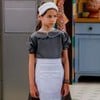 Anna (Mel Summers) com expressão triste e usando uniforme de empregada em cena da novela A Caverna Encantada