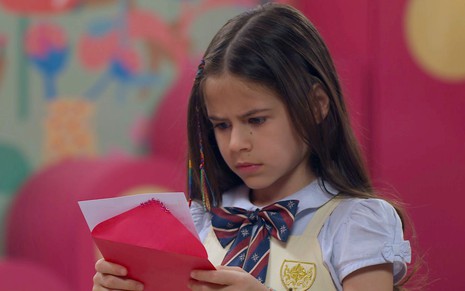 Anna (Mel Summers) segura uma carta em cena da novela A Caverna Encantada