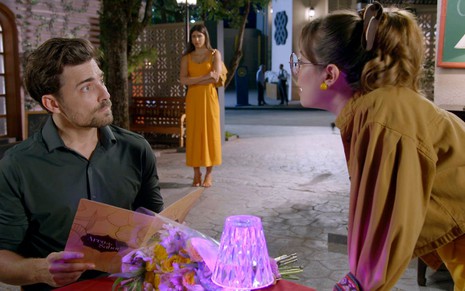 Gabriel (Miguel Coelho) olha para Betina (Thay Bergamim) em cena da novela A Caverna Encantada; Pilar (Isabela Souza) está no fundo