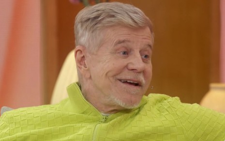 Miguel Falabella usa uma blusa verde limão e sorri no Encontro