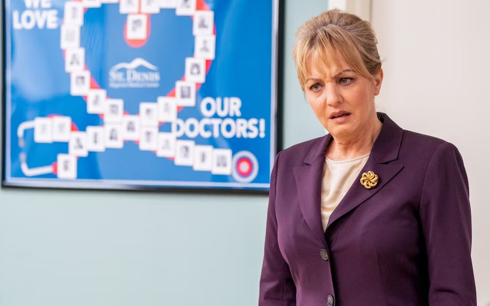 Wendi McLendon-Covey faz careta em um hospital cenográfico em cena da série St. Denis Medical