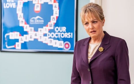 Wendi McLendon-Covey faz careta em um hospital cenográfico em cena da série St. Denis Medical