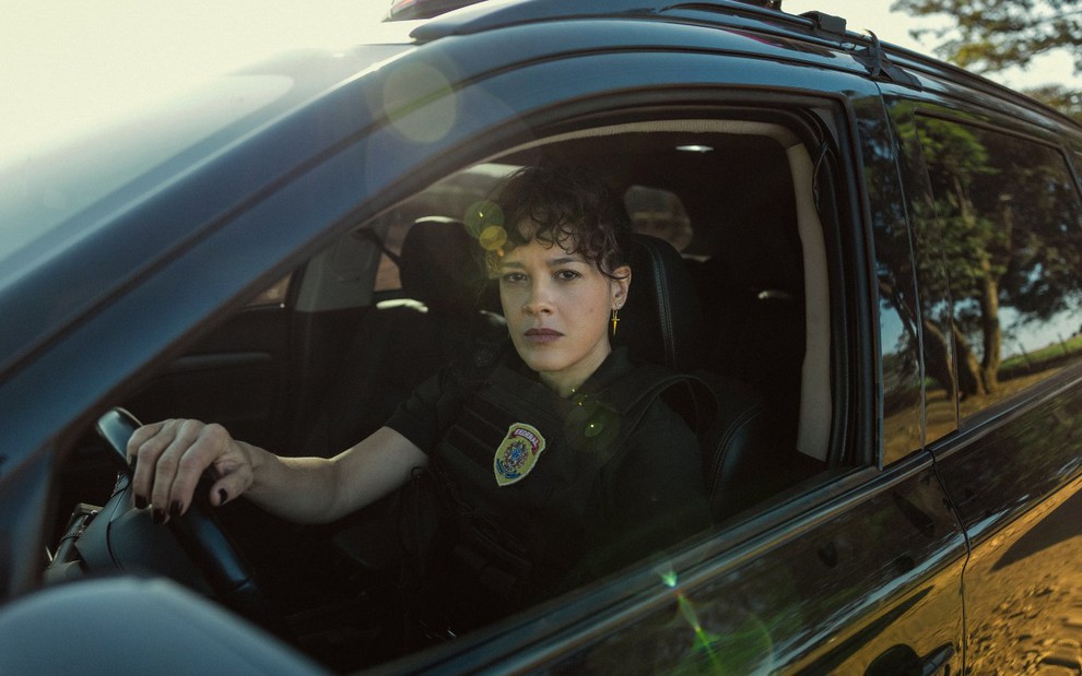 Maeve Jinkings veste uniforme policial e está dentro de uma viatura em cena de DNA do Crime