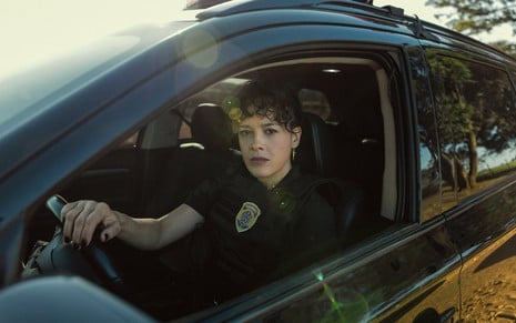 Maeve Jinkings veste uniforme policial e está dentro de uma viatura em cena de DNA do Crime