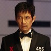 Lee Jung-jae tem expressão séria em cena de Round 6; ele veste um terno preto e tem o rosto levemente ensanguentado