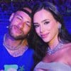 Neymar e Bruna Biancardi lado a lado na Sapucaí; ele usa abadá azul, e faz bico para a foto, e ela usa vestido prata e sorri