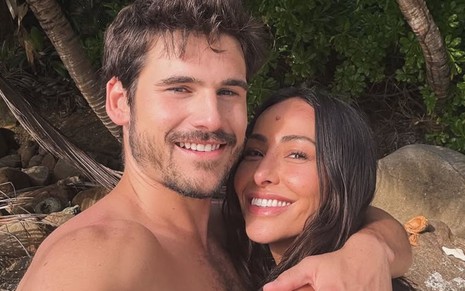 Nicolas Prattes e Sabrina Sato sorridentes, abraçados, em cenário paradisíaco