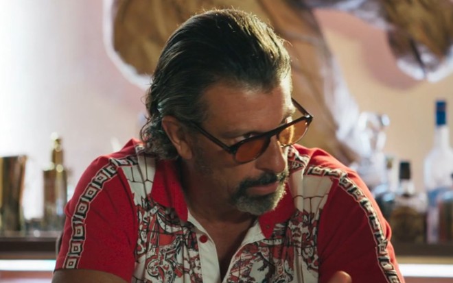 O ator Milhem Cortaz com expressão desconfiada em cena de Volta por Cima