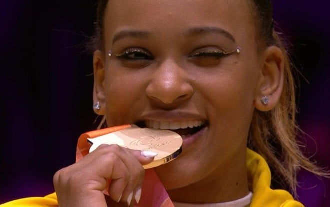 Imagem de Rebeca Andrade mordendo uma medalha
