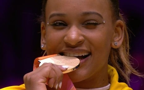 Imagem de Rebeca Andrade mordendo uma medalha