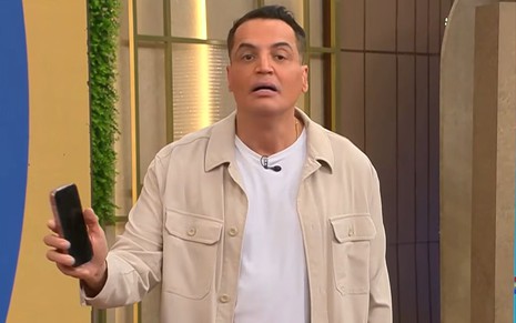 Leo Dias aparece com um celular na mão nos estúdios do Melhor da Tarde