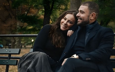 Paolla Oliveira e Diogo Nogueira em Nova York; os dois estão sentados em um banco, com roupas de frio, sorridentes enquanto Paola deita no ombro de Diogo