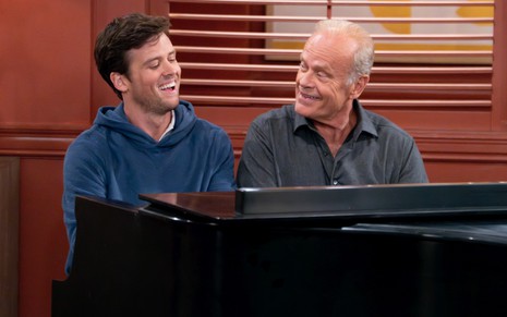 Jack Cutmore-Scott e Kelsey Grammer estão sentados e tocando piano em cena da série Frasier