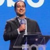 Paulo Marinho sorri e segura microfone com o logo da Globo em evento