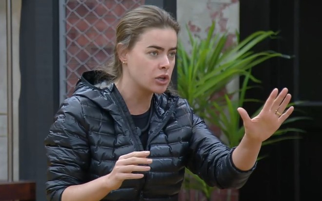 Rayanne Morais tem expressão de preocupação e a mão erguida em posição de evitar conflito na sala da casa do Power Couple