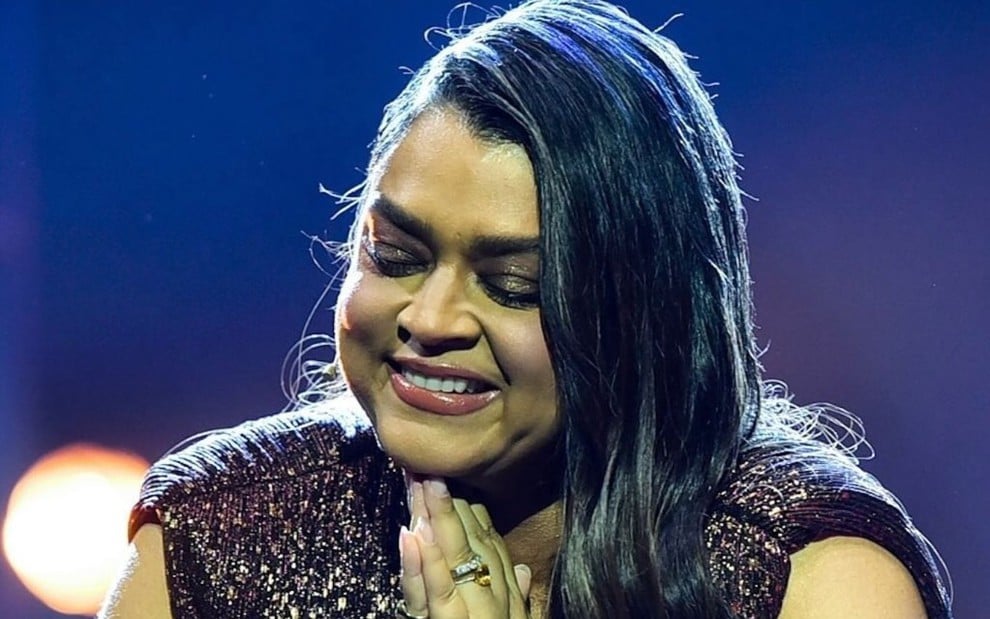 Preta Gil está com as mãos unidas em sinal de prece durante show