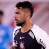 Jogador do Corinthians em campo, usando uniforme preto e branco com luvas pretas, em ação durante partida de futebol.