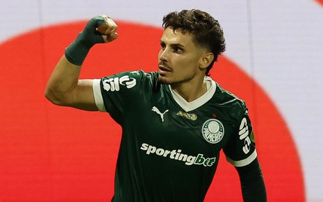 Raphael Veiga usa o uniforme verde do Palmeiras e está com braço levantado em sinal de força