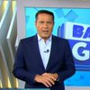 Um homem de terno e gravata em frente a um telão em que se lê: BALANÇO GERAL MANHÃ