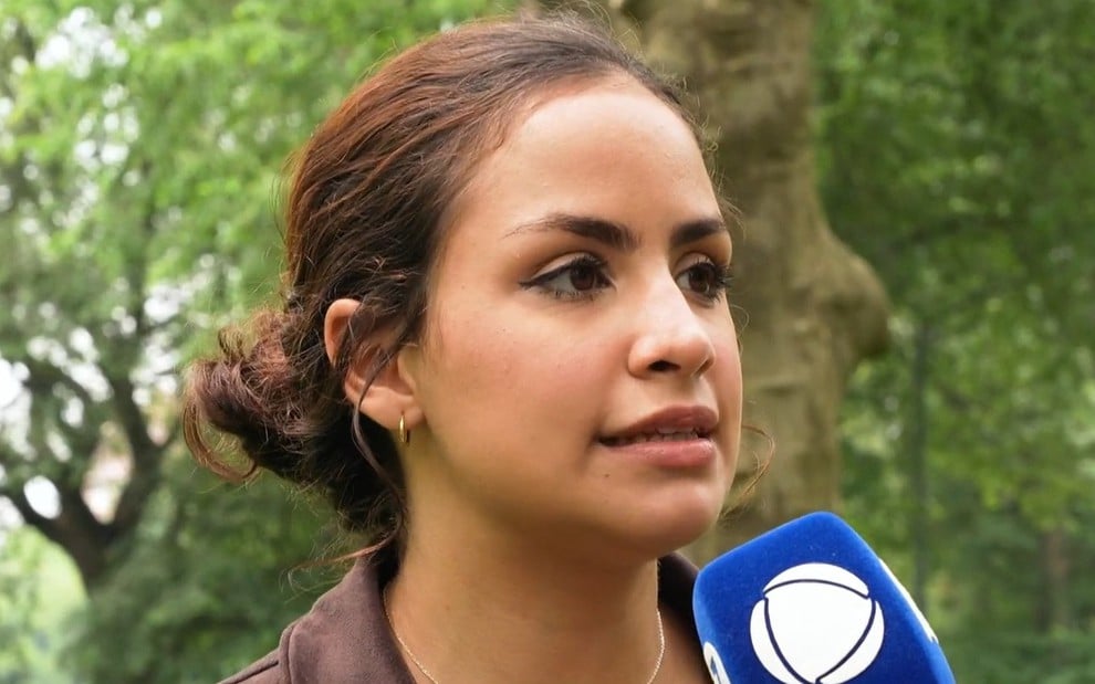 Laysa Peixoto fala com microfone com canopla da Record em um parque
