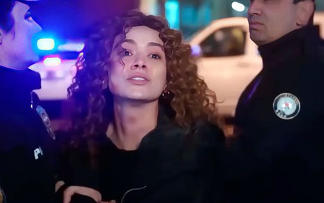 A atriz Serya Kaya como Sirin é segurada por dois policiais em cena de Força de Mulher