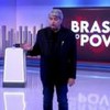 Homem de cabelos grisalhos, vestindo blazer preto e calça jeans, fala em estúdio moderno com o letreiro "BRASIL DO POVO" ao fundo.