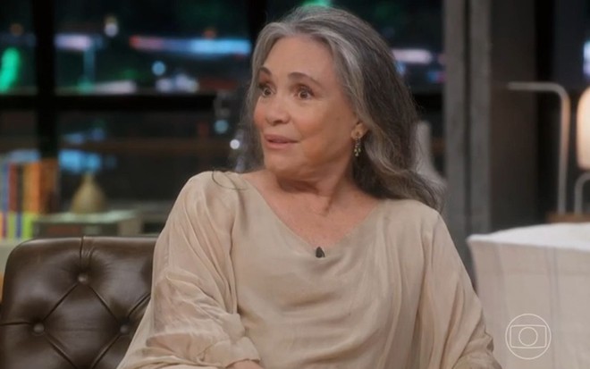 Regina Duarte com expressão séria e blusa bege no cenário do Conversa com Bial
