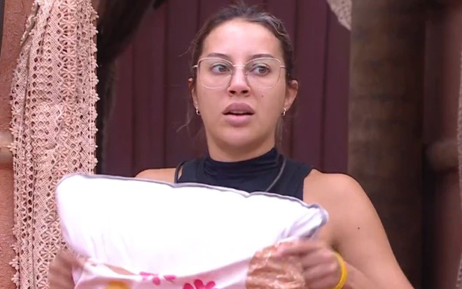 Renata Saldanha com feição surpresa, arrumando uma fronha no quarto Nordeste no BBB 25