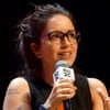 Manuela Dias fala em microfone em um fundo preto no Rio2C