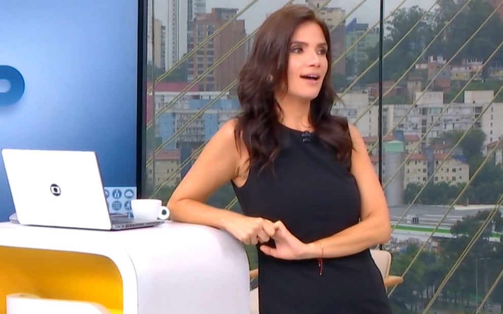 Sabina Simonato usa um vestido preto e está apoiada na bancada do Bom Dia São Paulo