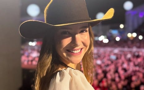 Sammy Sampaio posando com chapéu de boiadeira, em frente a uma plateia, sorrindo para a câmera