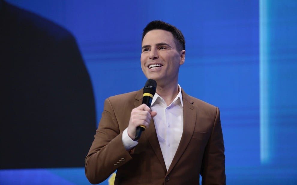 Luiz Bacci fala sorridente em microfone durante evento de apresentação da nova grade do SBT