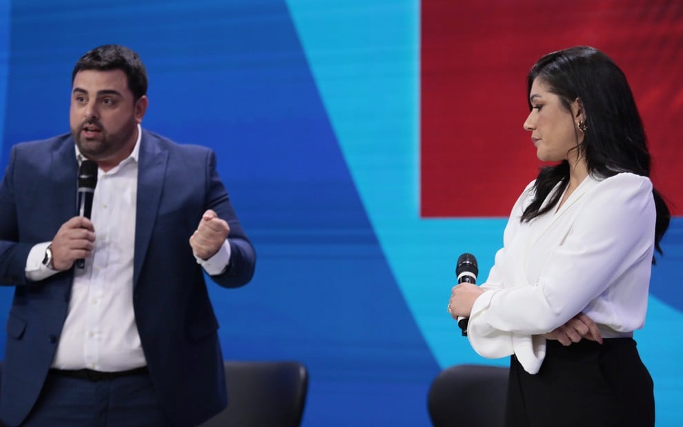 Macedão da Chinelada e Daniele Brandi falam em seus microfones durante coletiva de imprensa