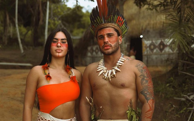 Isabelle Nogueira e Lucas Guimarães posam com trajes indígenas em uma aldeia