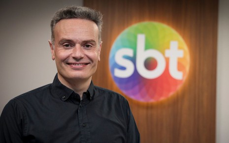 Leandro Cipoloni à frente da logo do SBT