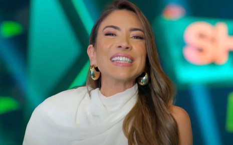 Patricia Abravanel sorridente no cenário do Show do Milhão