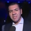 Daniel Abravanel fala em microfone e olha para a câmera com expressão de contragosto
