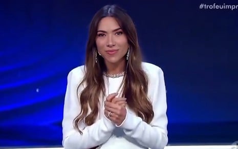 Patricia Abravanel tem expressão séria e segura as duas mãos próximas ao peito